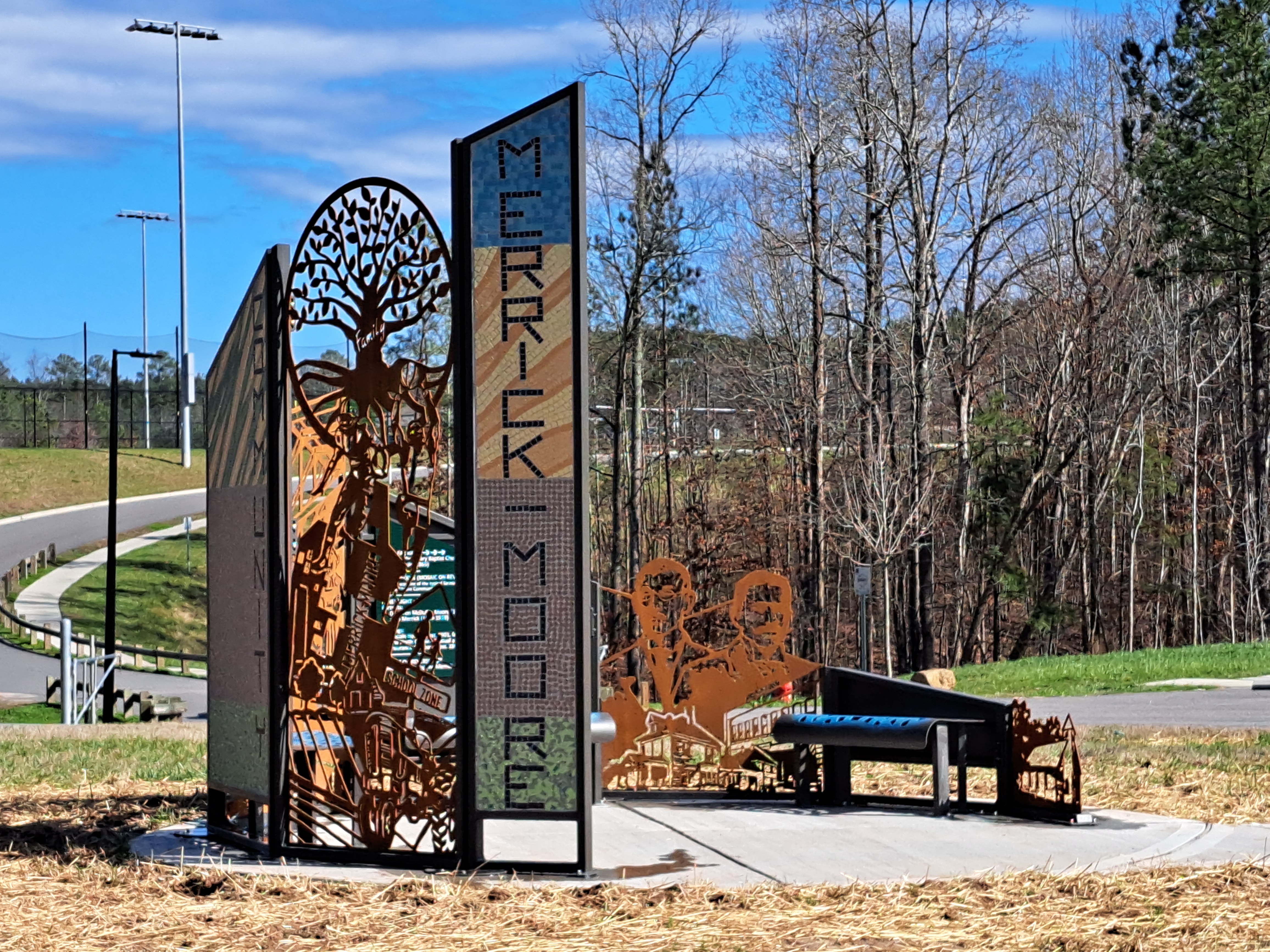 Metal and mosaic panels forming a large semi-oval structure at the entry of Merrick-Moore Park