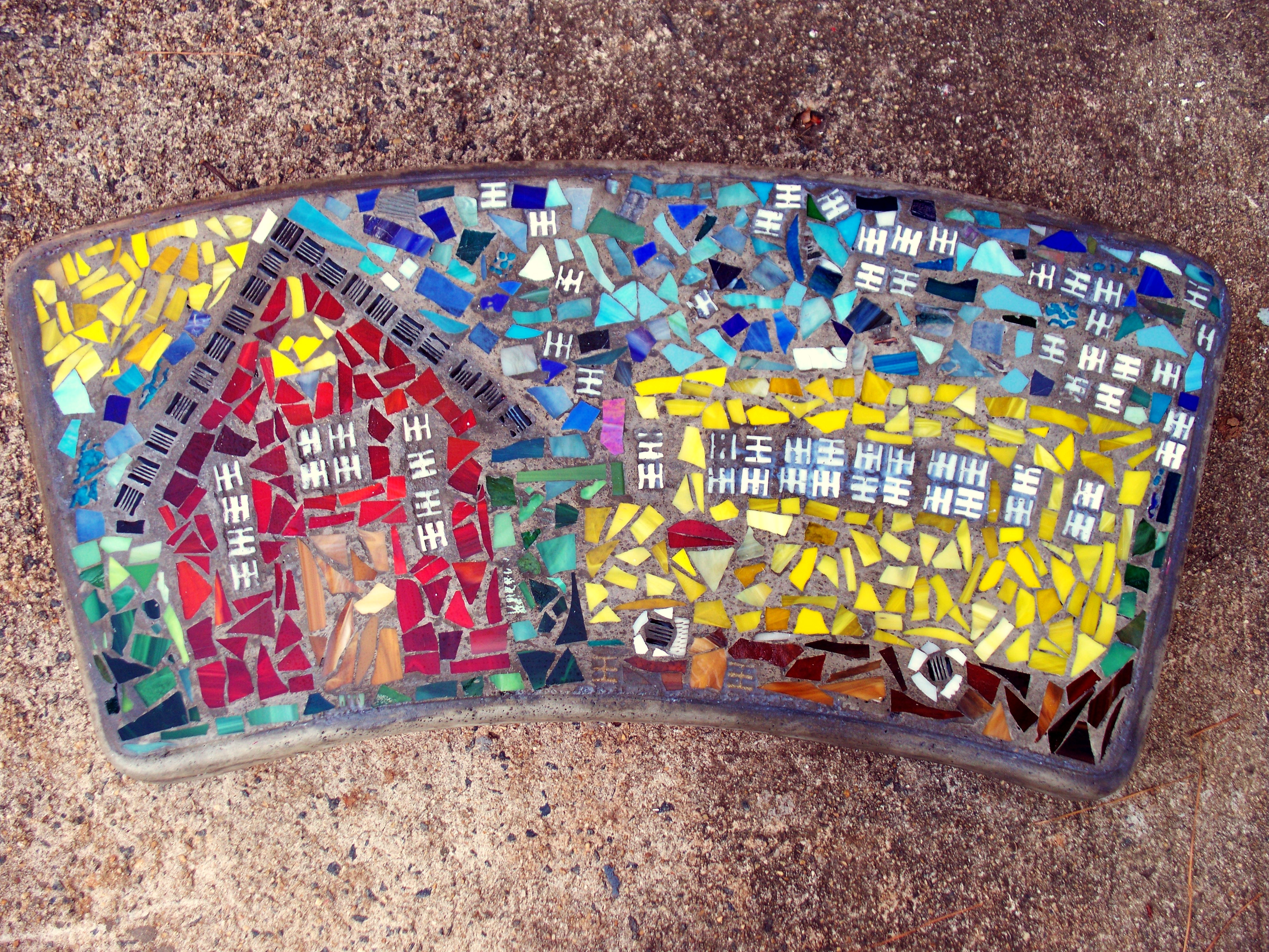 concrete bench top with embedded colorful mosaics showing a red school house and yellow bus