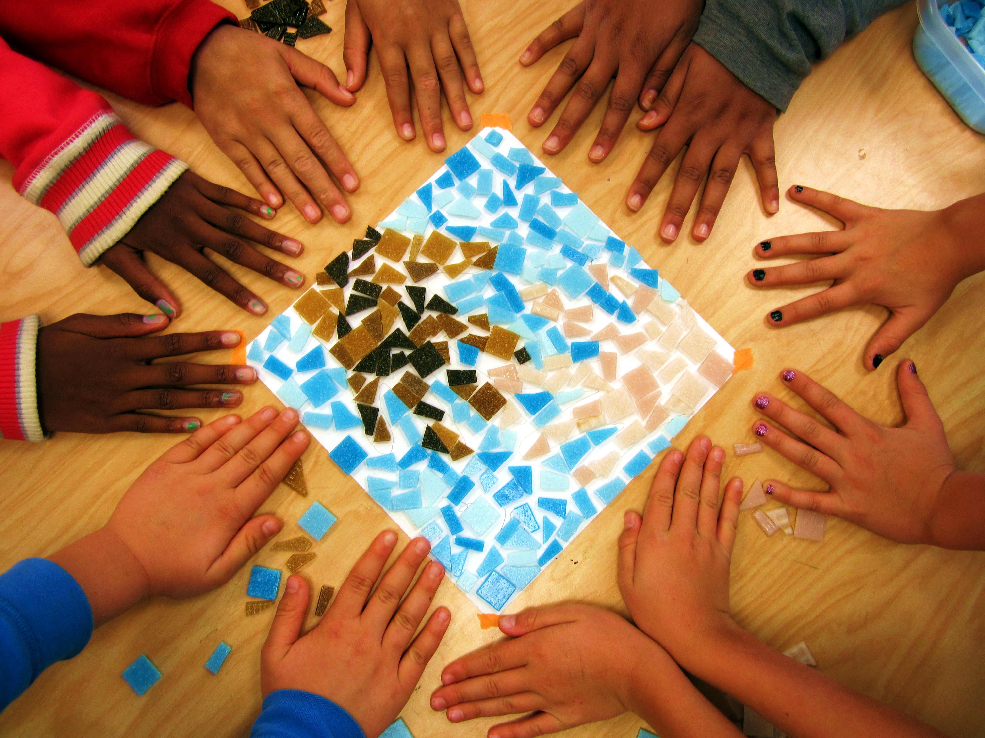 diverse skin colors of student hands surrounding a mosaic of hands